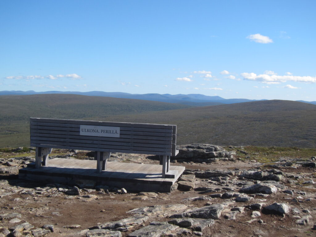 Kiilopään huipulla oleva penkki ja sen takana oleva avotunturimaisema Urho Kekkosen kansallispuiston syrjävyöhykkeelle päin