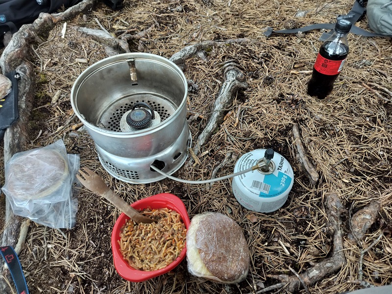 Kuvassa neulaspohjalla Trangia, jolla on juuri keitetty kuvassa myös näkyvä bologneseannos.